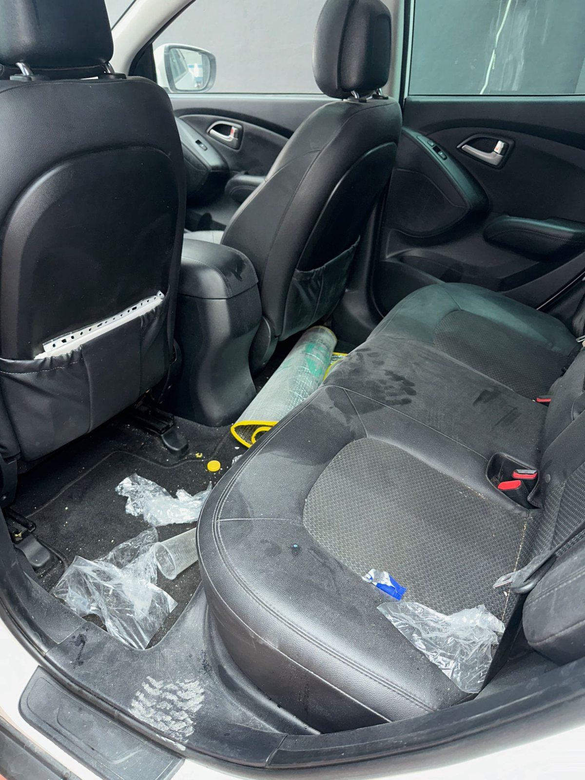Interior trasero sucio, con basura y manchas en los asientos