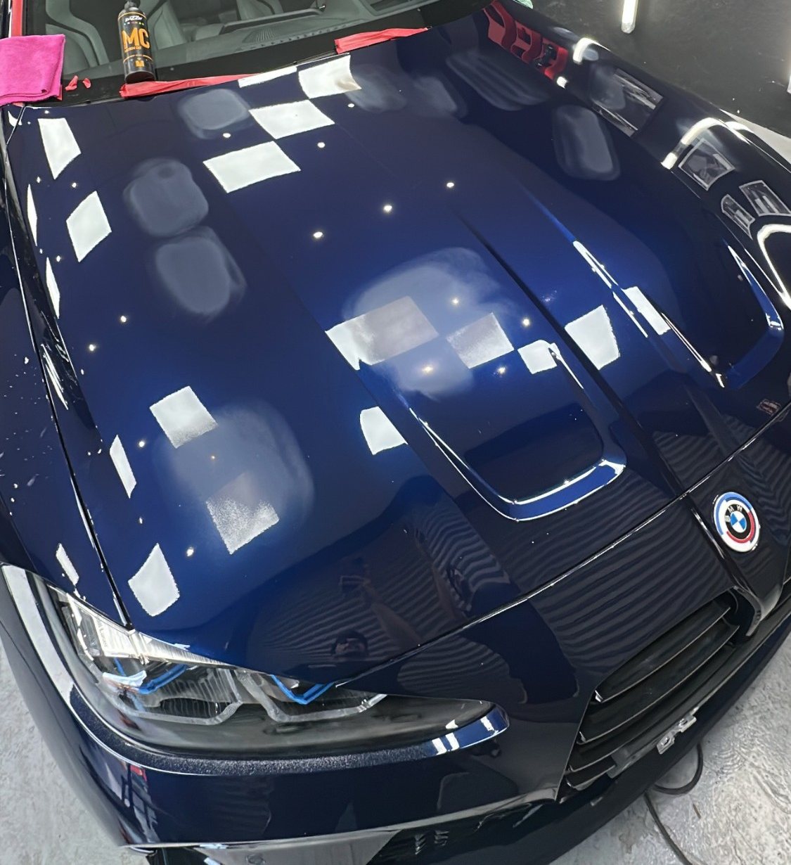 Capó de un BMW M4 azul durante la corrección de pintura